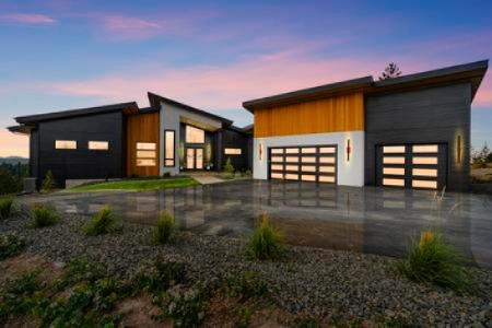 A modern house with three garage doors and a driveway.