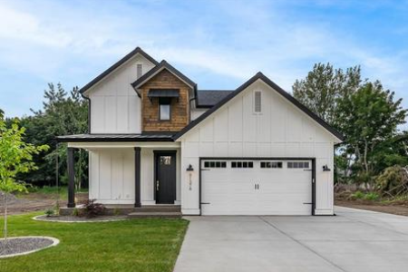 A white house with two garage doors and grass in front of it.